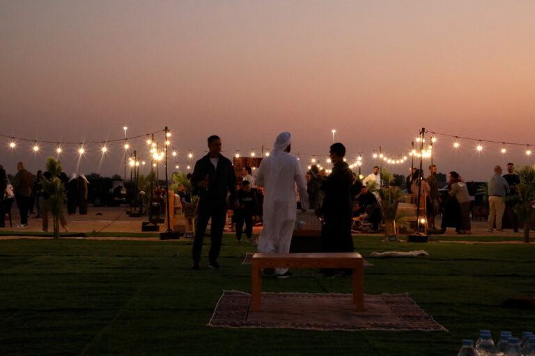 Elegant outdoor catering setup in Dubai at sunset with guests dining under string lights
